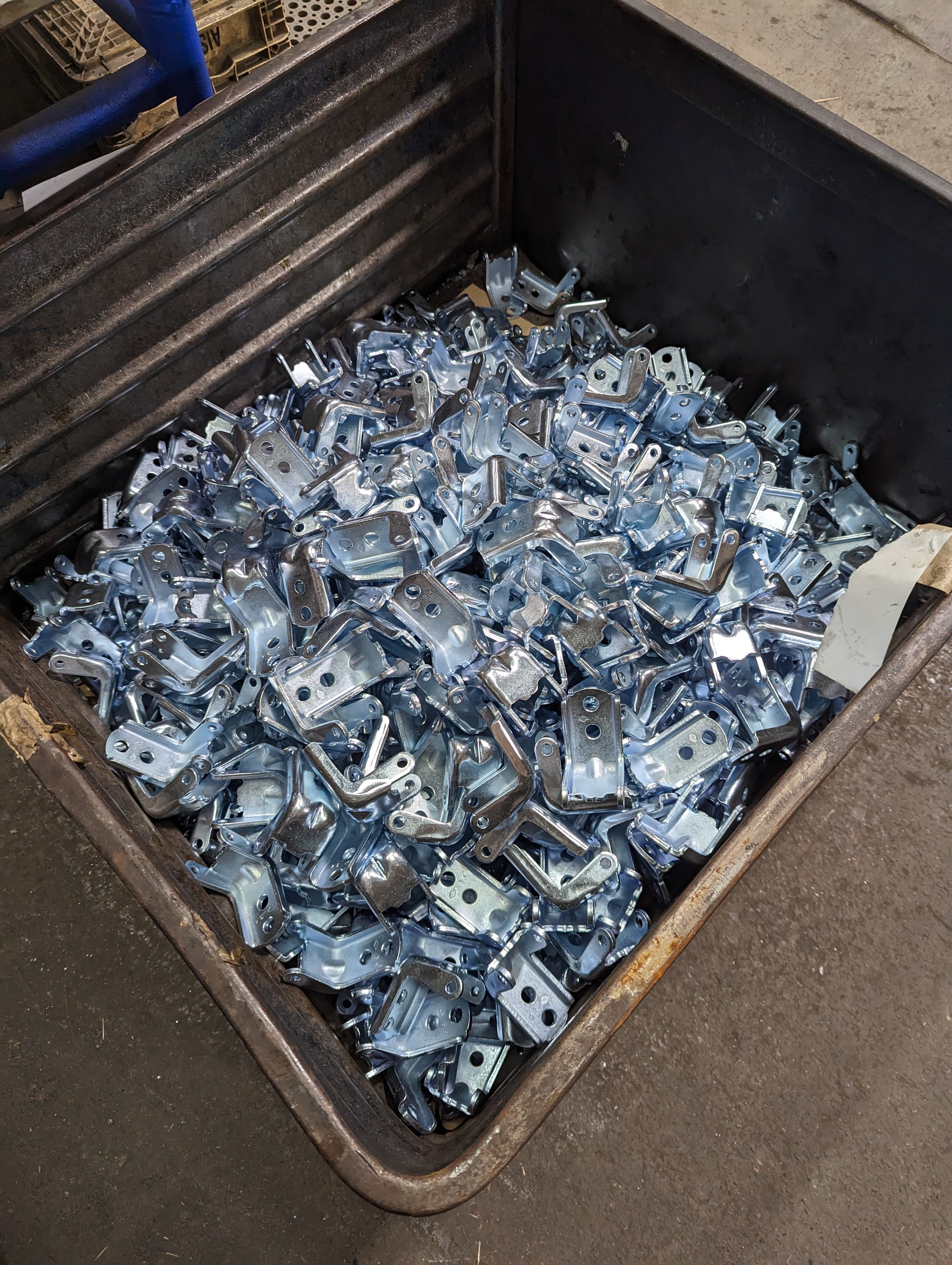 Bin of freshly zinc plated automotive brackets — the end product of a properly controlled zinc bath